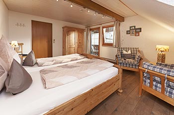 Schlafzimmer mit Doppelbett, Sitzecke und Zugang zum Balkon