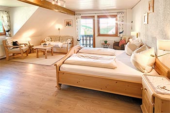 Schlafzimmer mit Doppelbett, Sitzecke und Zugang zum Balkon