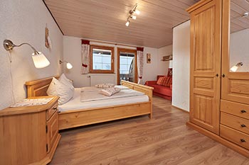 Schlafzimmer mit Doppelbett, Schlafsofa und Zugang zum Balkon