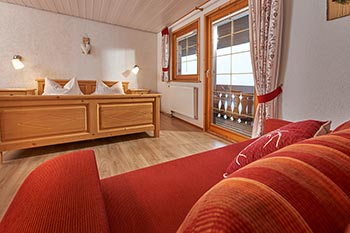 Schlafzimmer mit Doppelbett, Schlafsofa und Zugang zum Balkon